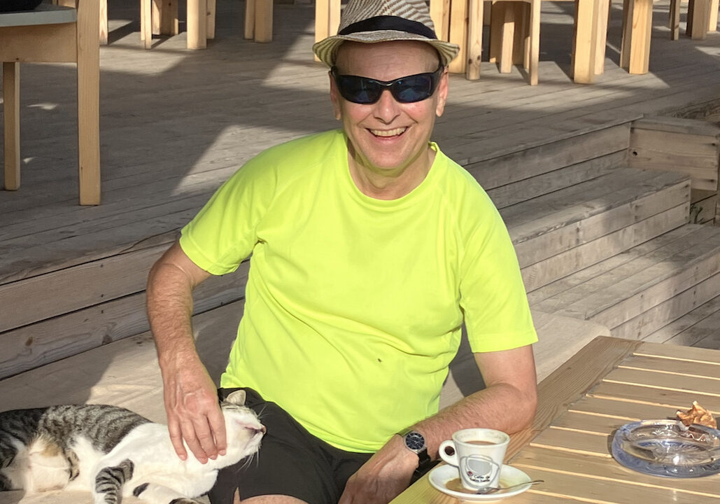 Strahlender Kunde mit Katze am Strand von São Pedro